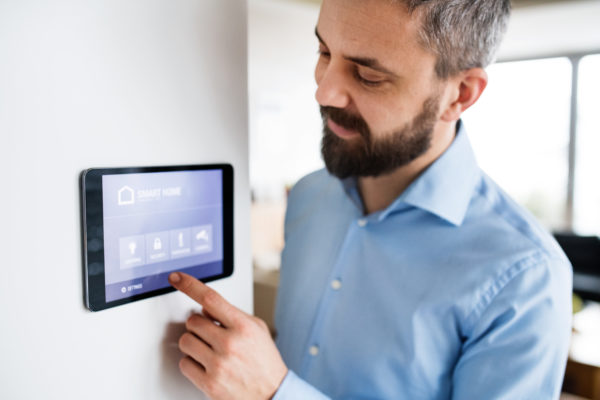 An handsome man pointing to a tablet with smart home control system at home.
